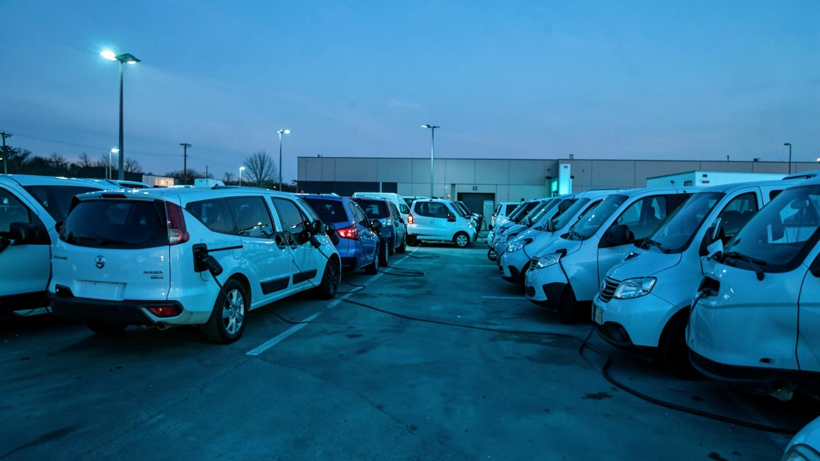 Electric fleet vans charging at a depot at dusk